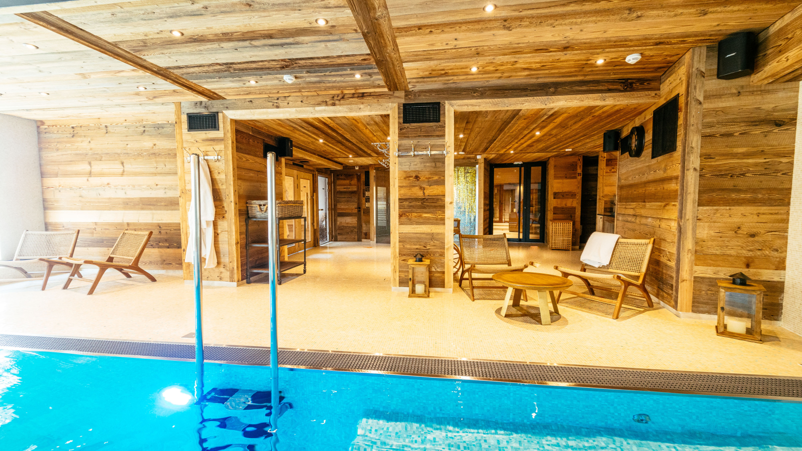espace détente en bois avec piscine chauffée et coin salon.