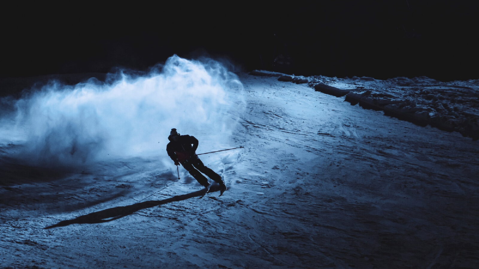 Skieur descendant une piste ouverte en nocturne sur le domaine skiable alpin du Grand-Bornand
