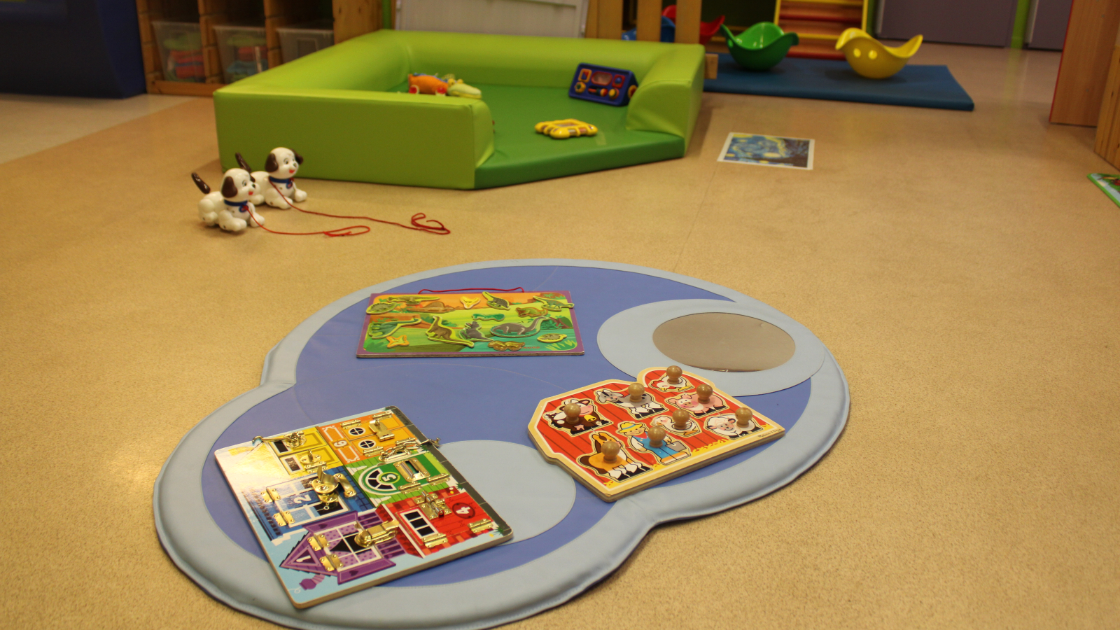 Zone de jeux au sol avec tapis, jeu de puzzle, jeu d'éveil, jeu à bascule.