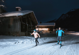 Couple pratiquant le ski nordique en nocturne sur les pistes du domaine du Grand-Bornand