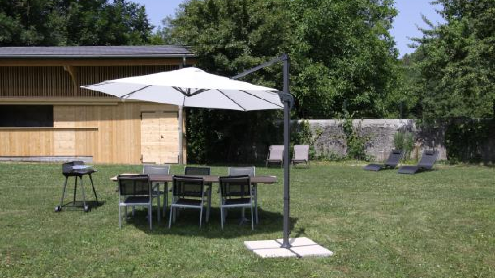 Jardin avec barbecue et chaises longues